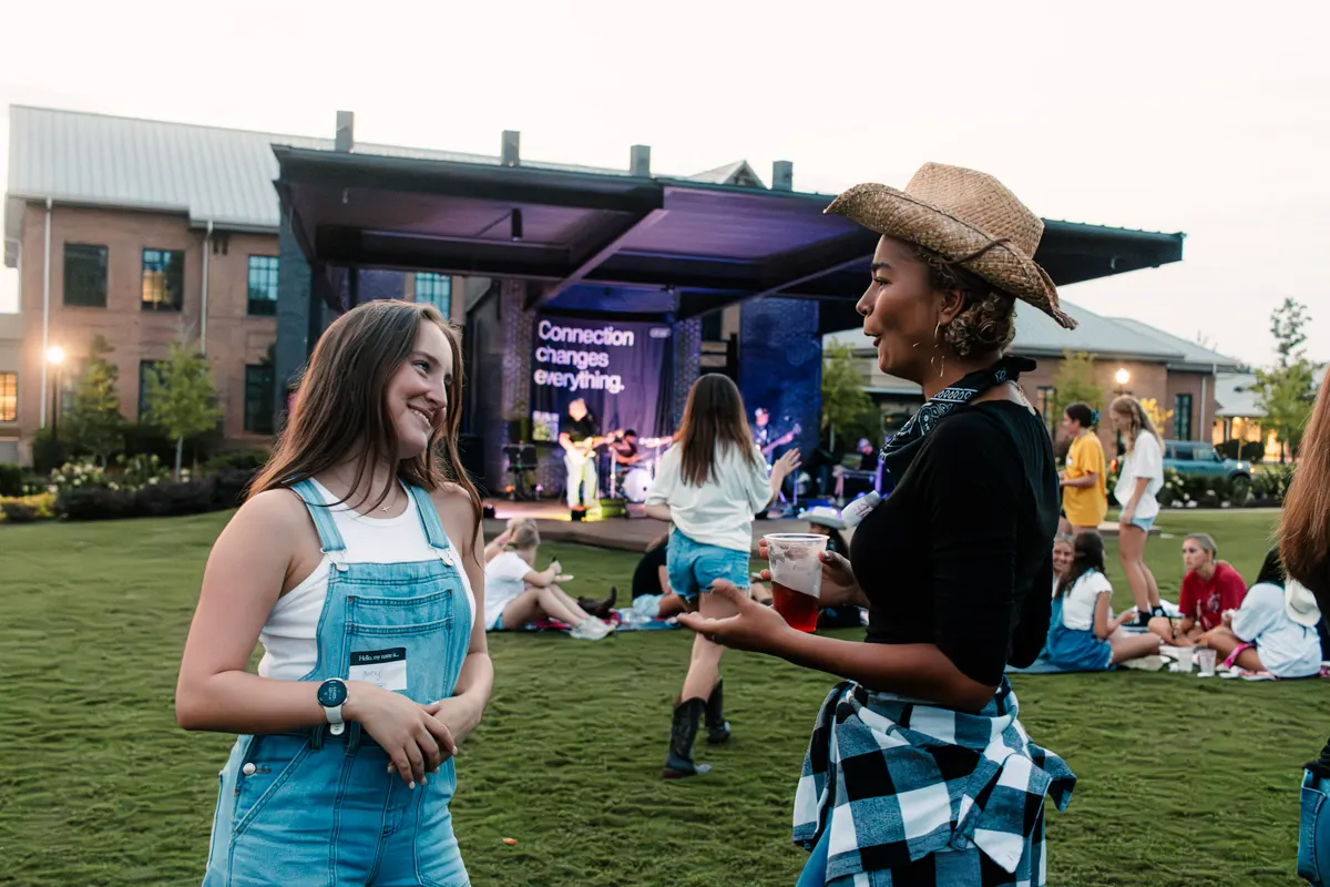Students talking on a lawn at an outdoor evening Whisper event