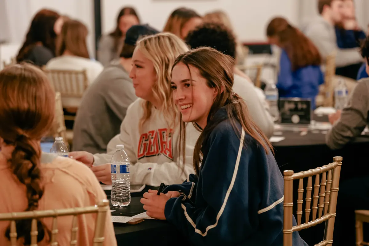 Students smiling around a table at a Whisper gathering