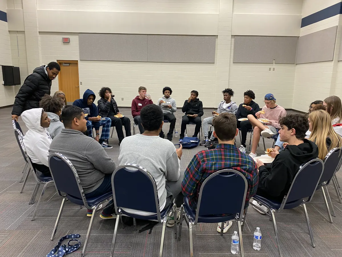 Students sitting in a circle of chairs at a Whisper gathering
